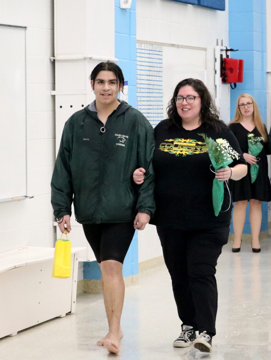 Jose Garcia(24) walks with his parent during the senior recognition portion of the Jan. 31 swim meet. 