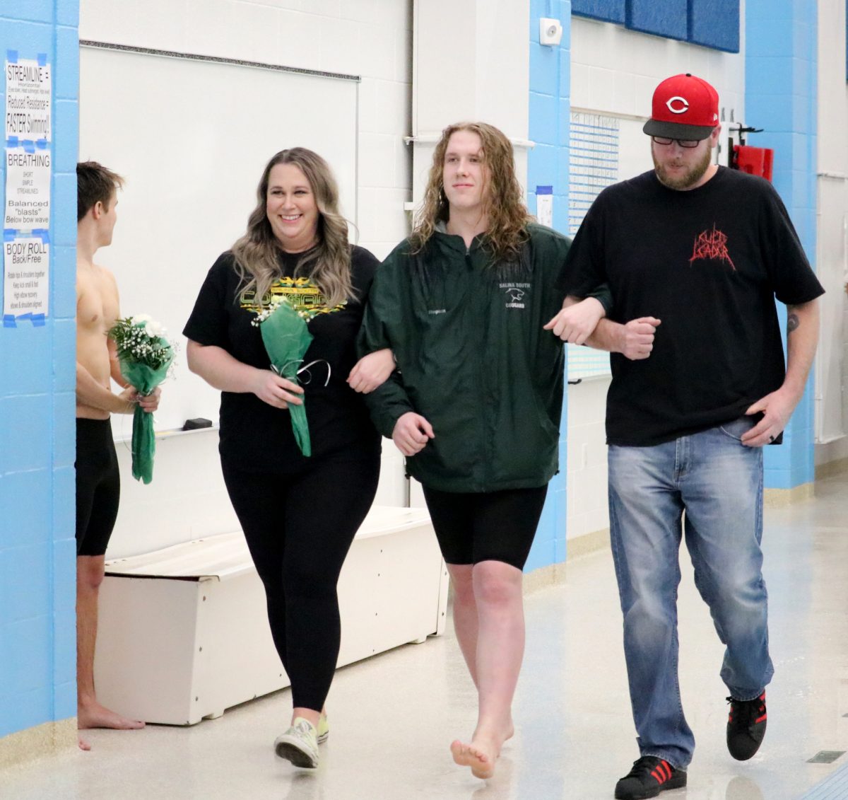 Kasen Stegman(24) walks with his parents during the senior recognition portion of the Jan. 31 swim meet. 