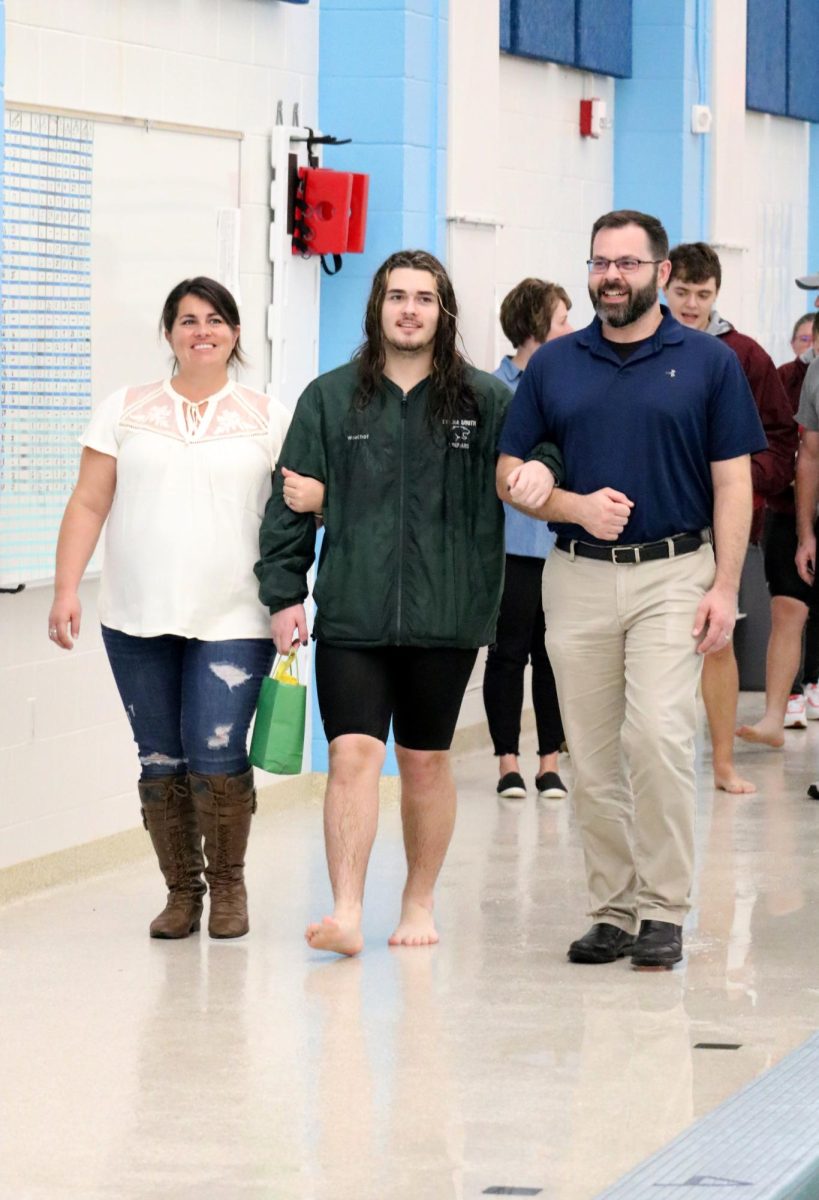 Landon Woellhof(24) walks with his parents during the senior recognition portion of the Jan. 31 swim meet. 