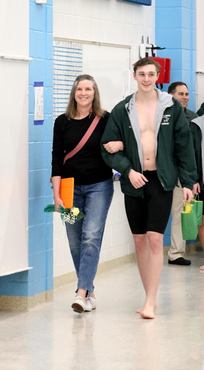 Lane Brucker(24) walks with his parent during the senior recognition portion of the Jan. 31 swim meet. 
