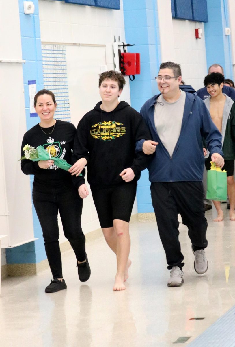 Marcos Lujan(24) walks with his parents during the senior recognition portion of the Jan. 31 swim meet. 