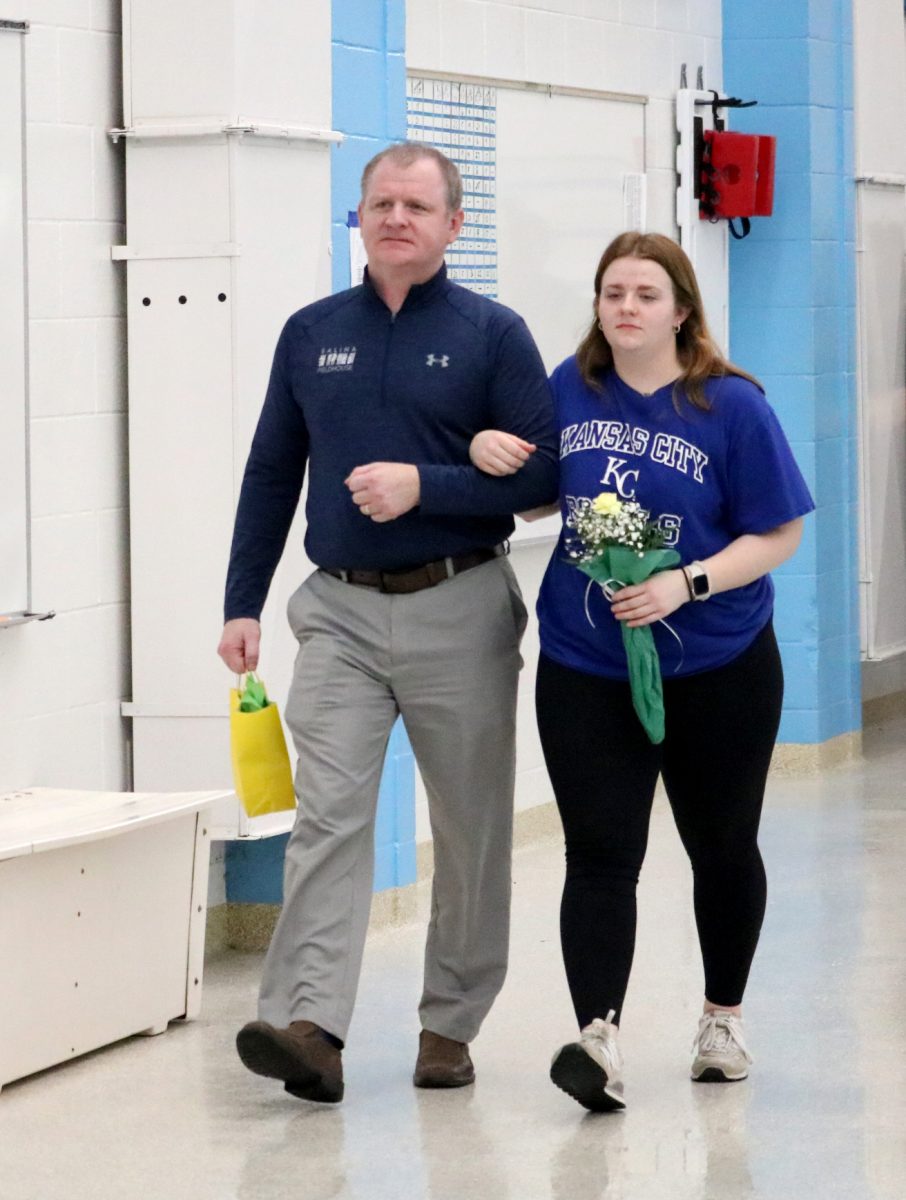 Maycie Sheele(24) walks with her parent during the senior recognition portion of the Jan. 31 swim meet. 