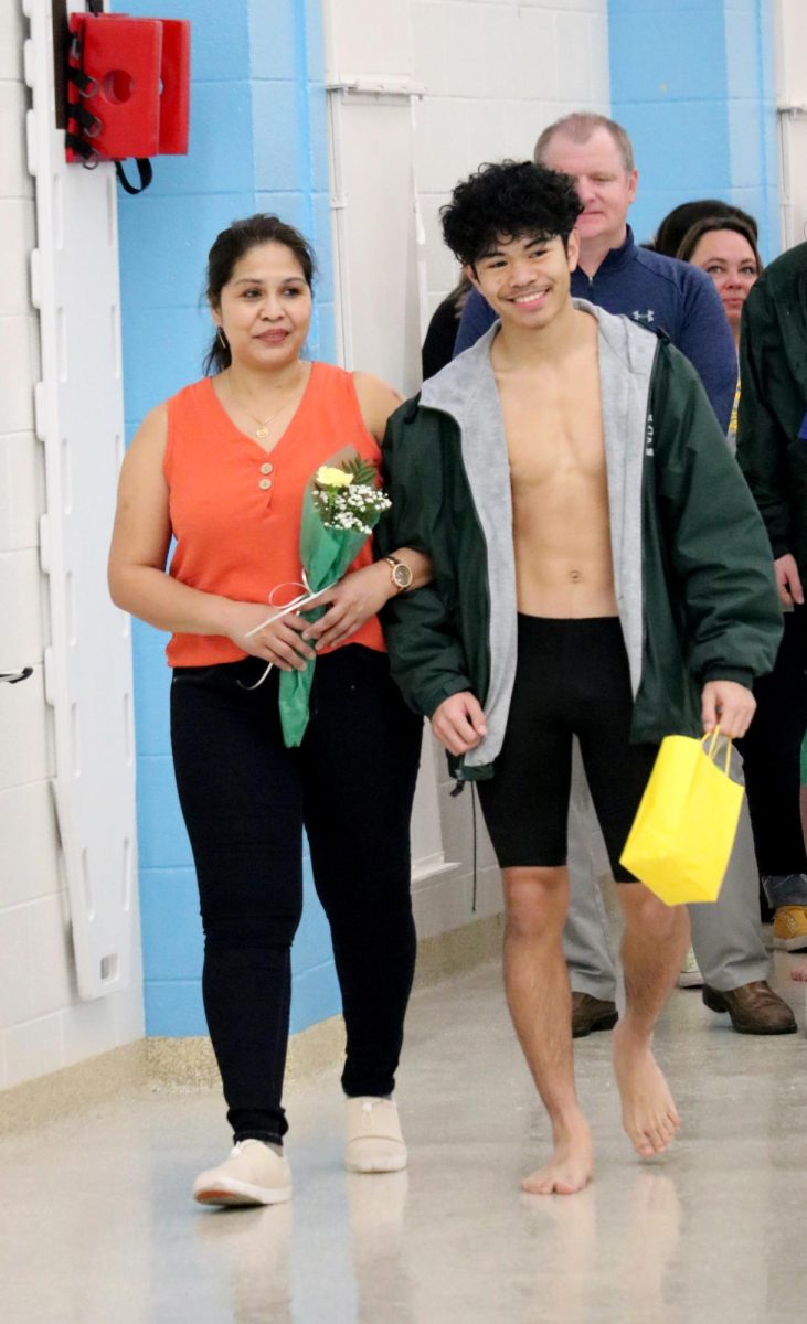 Xavyer Nouanlasy(24) walks with his parent during the senior recognition portion of the Jan. 31 swim meet. 
