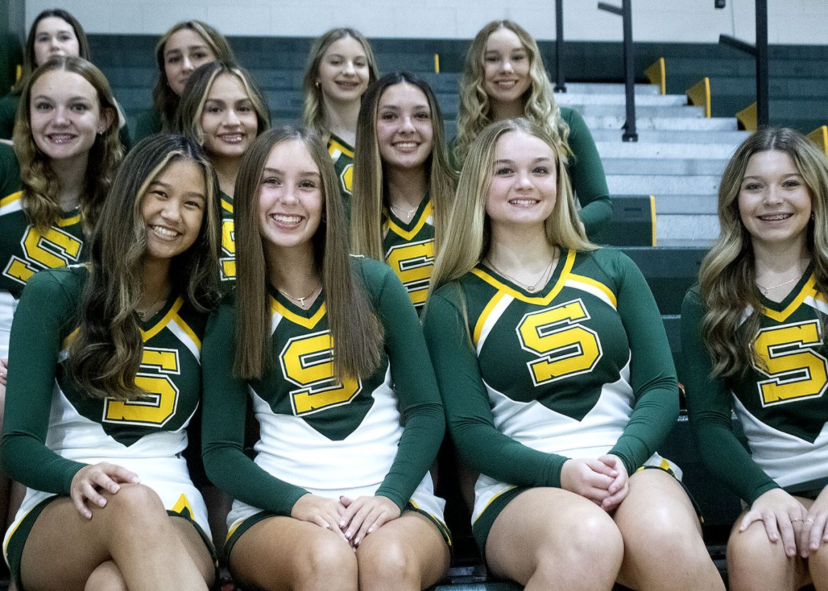 Cheerleaders wait on the bleachers to take sports pictures.