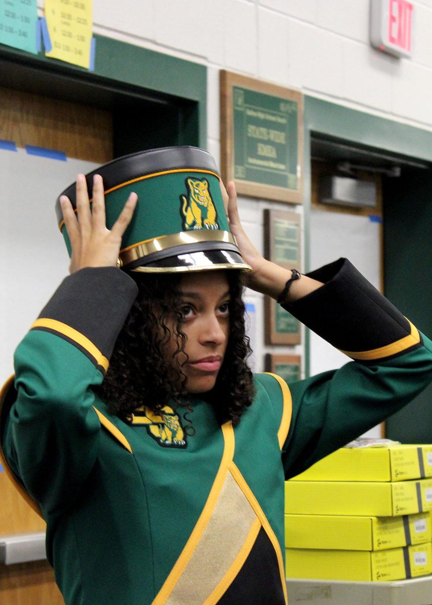 Kamryn Watts ('25) places her hat on during uniform checkout. 