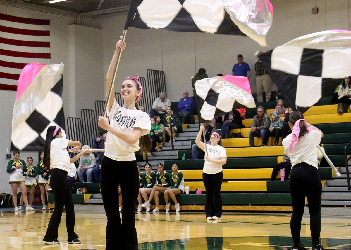 Trinity Birch ('26) and Hailie Michels ('29) hold up their flags and wait for their cue while Lourdes Martin-Escobedo ('28) and Aliana Rios ('26) start the performance.